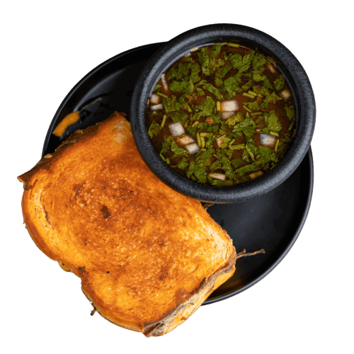 Birria sandwich with melted cheese and crispy bread, served with consommé.
